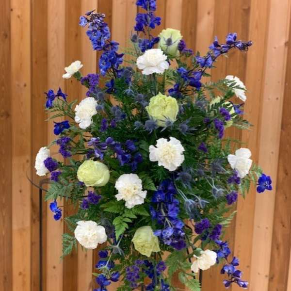 Tall blue and white floral standing spray on a metal easel