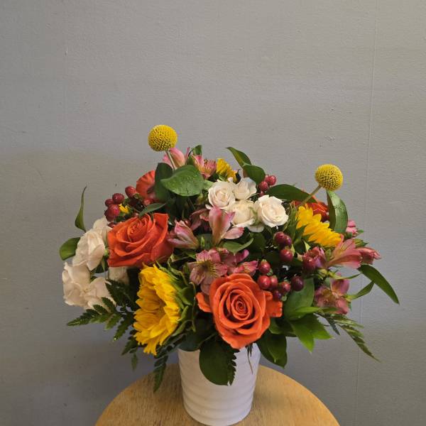 Mixed bouquet of orange and white roses with yellow blooms in a white vase