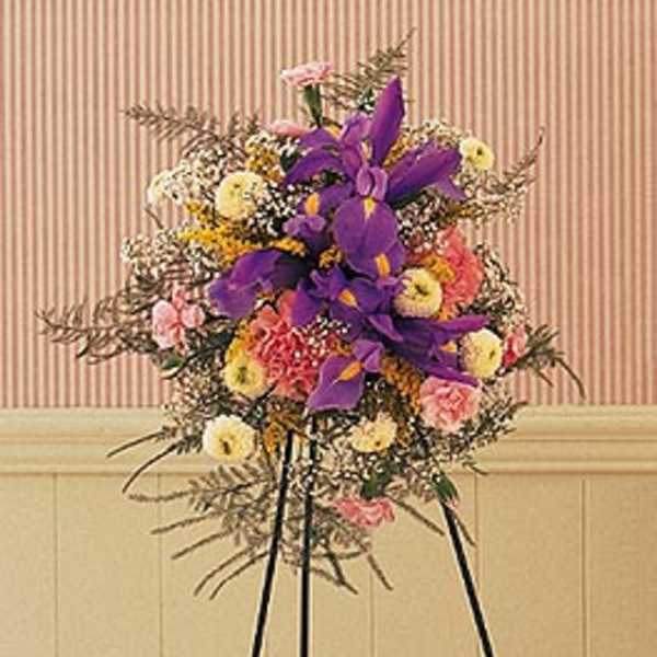 Standing floral spray with purple and pink flowers on a black easel