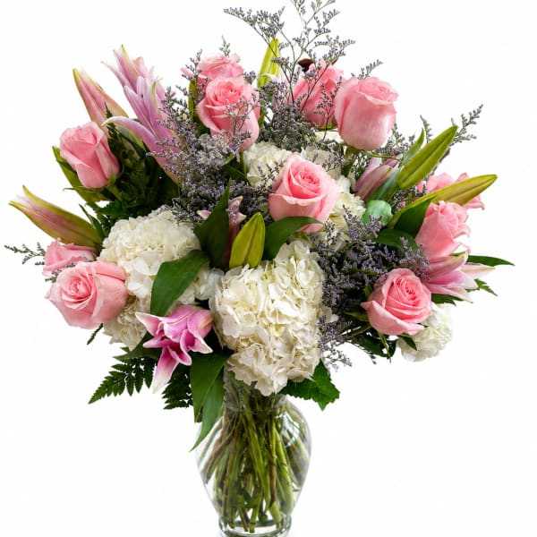 Pink roses and white hydrangeas arranged in a clear glass vase
