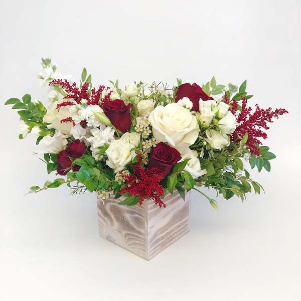 Bouquet of red and white roses in a square wooden vase