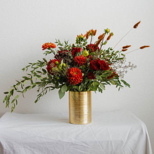Red and orange flowers arranged in a gold vase