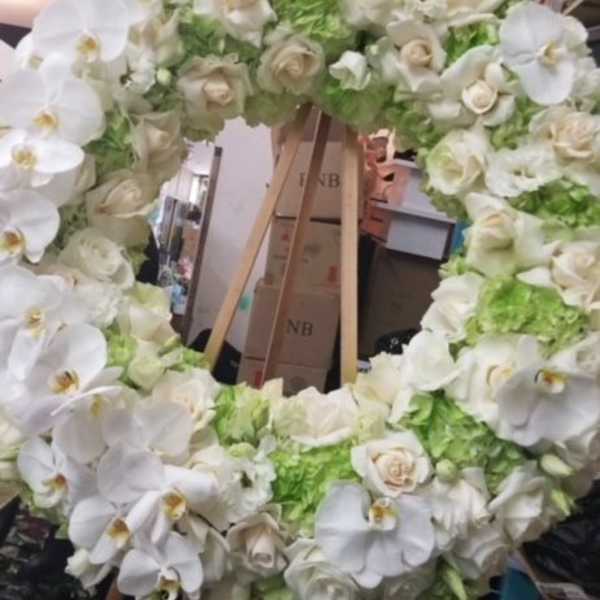 Large white floral wreath on a wooden easel