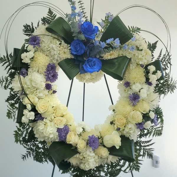 Large floral wreath with blue and white flowers on a stand