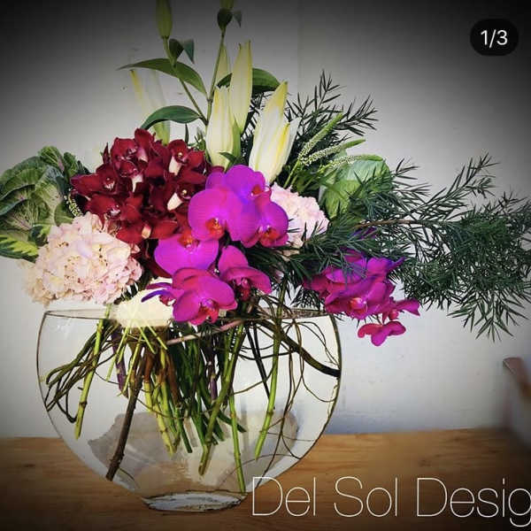 Mixed orchid arrangement in a clear glass bowl vase