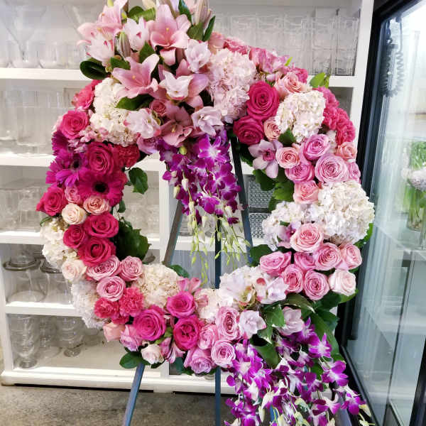 Large pink floral wreath on an easel with cascading purple orchids