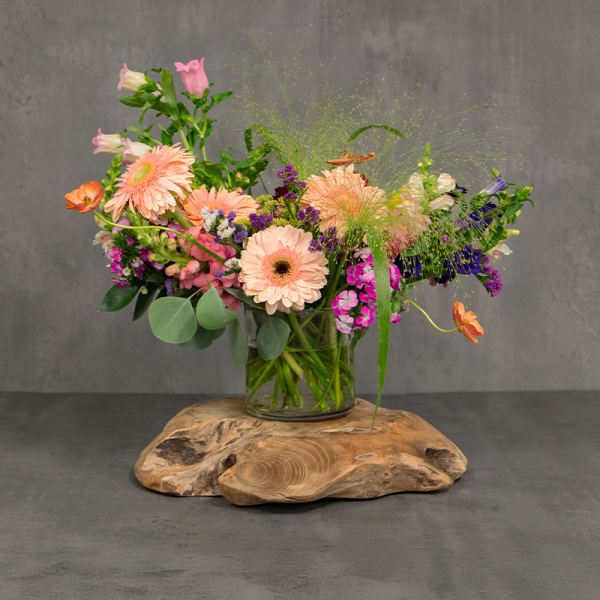 Mixed bouquet of peach, pink, purple, and orange flowers in a glass vase
