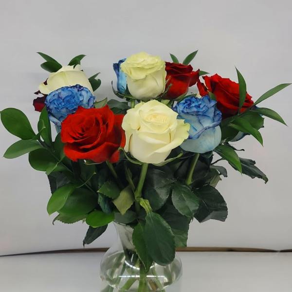 Bouquet of red, white, and blue roses in a clear glass vase