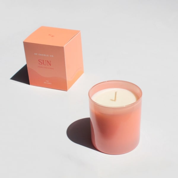 Pink candle in a glass jar beside its box