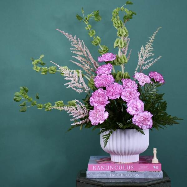 Pink carnations in a white vase with airy pink filler flowers