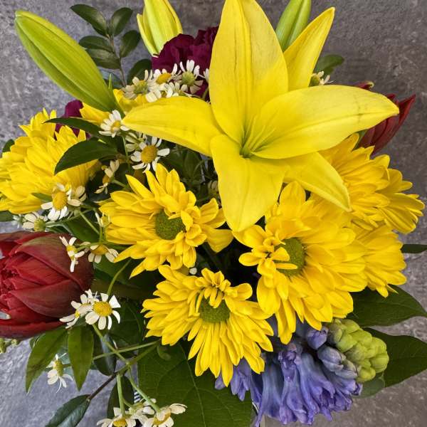 Bouquet of yellow lilies, daisies, and red blooms