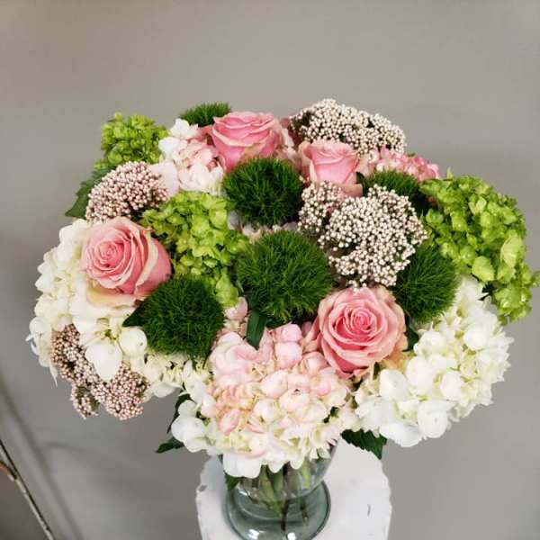 Pink roses and white hydrangeas arranged in a glass vase