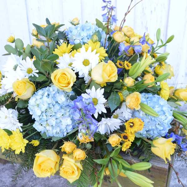 Bouquet of yellow roses, blue hydrangeas, and white daisies
