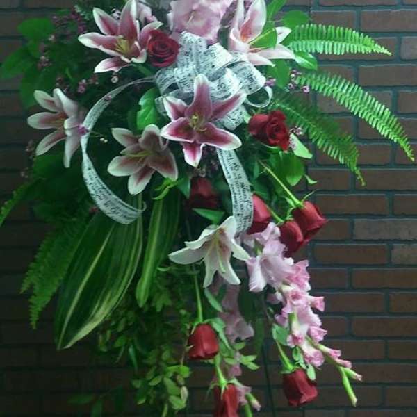 Standing floral spray with pink lilies, red roses, and purple spikes