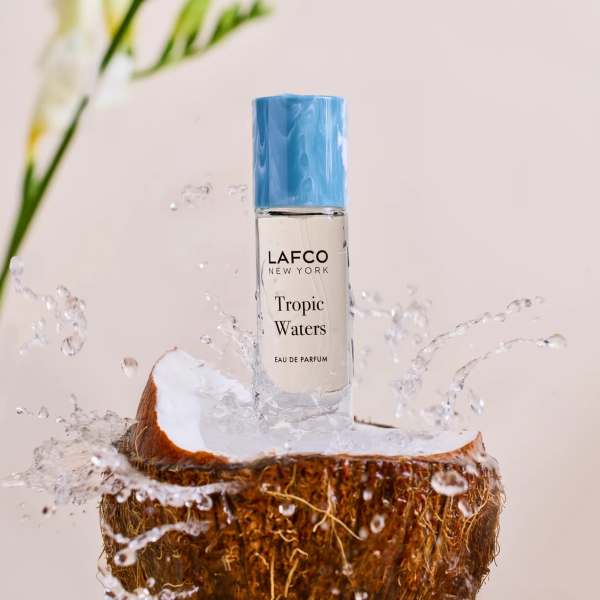 Perfume bottle on a coconut half with water splashing around it