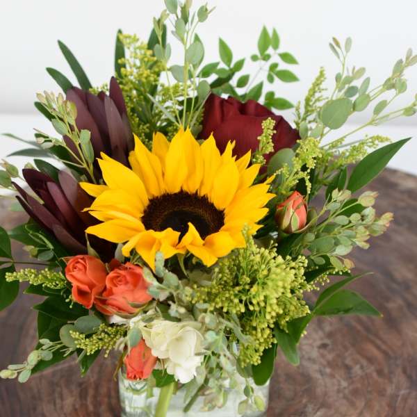 Sunflower and rose arrangement in a square glass vase
