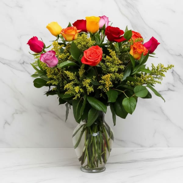 Mixed roses in a clear glass vase with yellow filler flowers