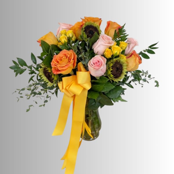 Bouquet of roses and sunflowers in a glass vase with a yellow ribbon