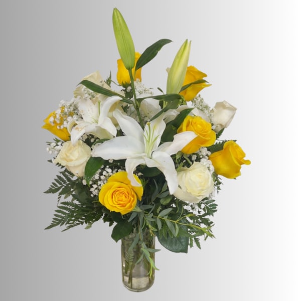 Yellow and white roses with white lilies in a glass vase
