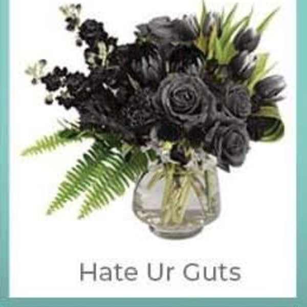Black floral arrangement in a glass vase with green foliage
