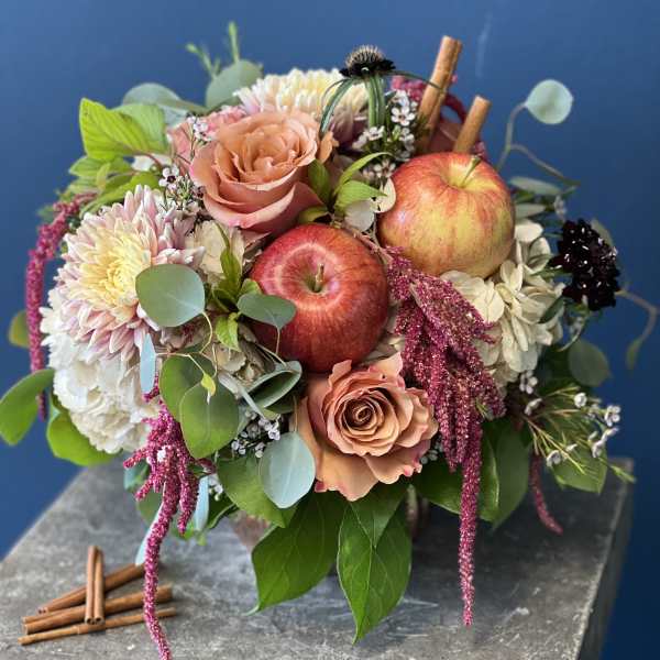 Mixed bouquet with roses, chrysanthemums, and apples on a stone pedestal