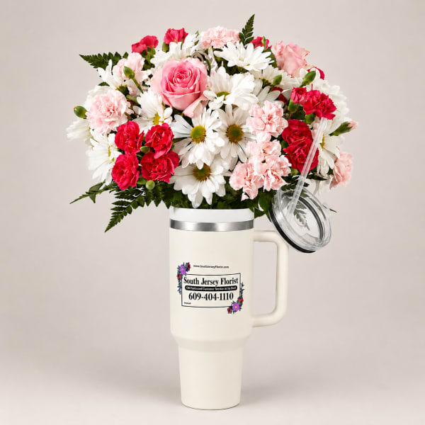 Bouquet of pink roses, carnations, and white daisies in a handled tumbler cup