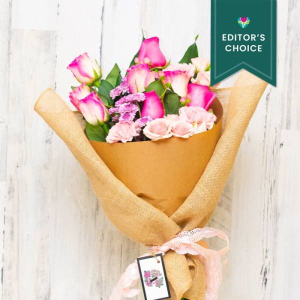 Bouquet of pink and white roses wrapped in brown paper and burlap
