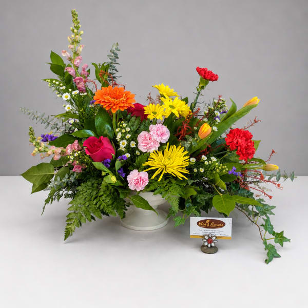 Colorful mixed flower arrangement in a white pedestal vase