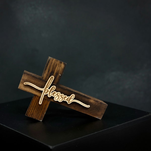 Wooden cross sign with the word blessed on a dark pedestal