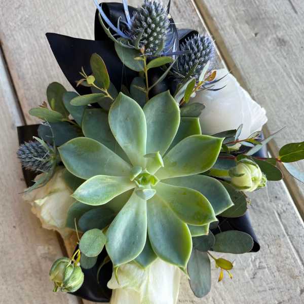 Succulent bouquet with blue thistle and white blooms wrapped in black paper