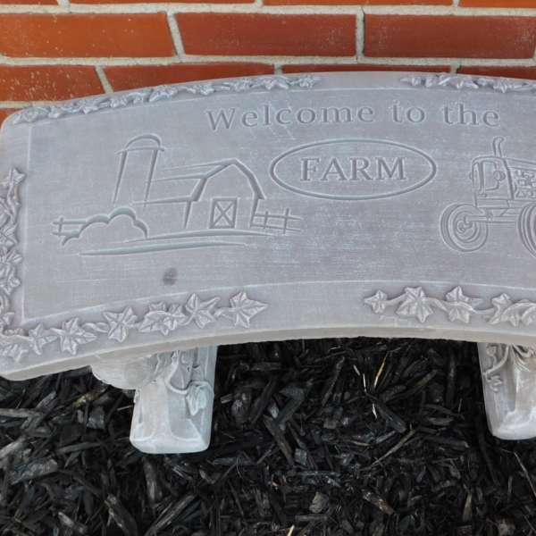 Stone sign reading welcome to the farm with a tractor and barn design