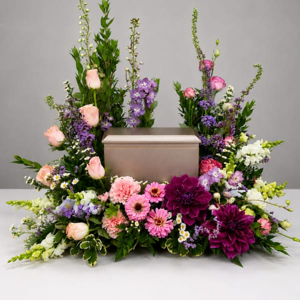 Floral arrangement surrounding a silver urn with pink, purple, and white blooms