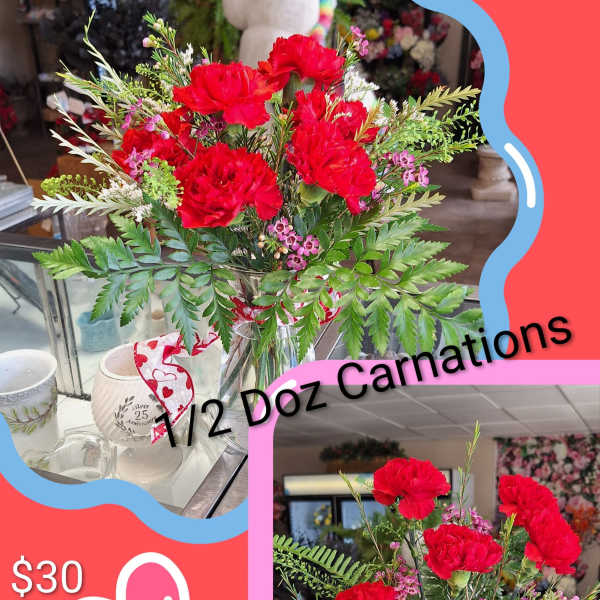 Red carnation bouquet in a glass vase with a heart ribbon