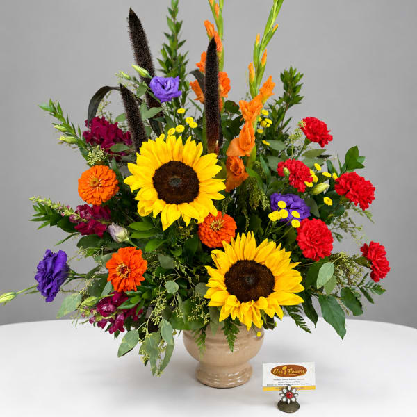 Bright mixed bouquet with sunflowers, orange and red blooms in a beige vase