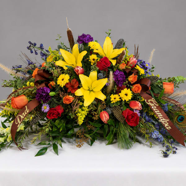 Large colorful floral arrangement with lilies, roses, and ribbons