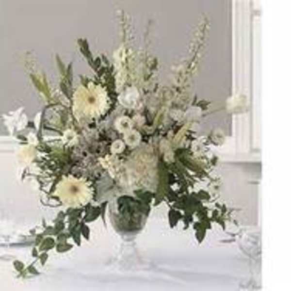 White floral arrangement in a clear vase with tall stems and trailing greenery
