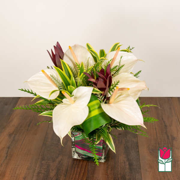 White calla lilies and burgundy tropical flowers in a glass vase