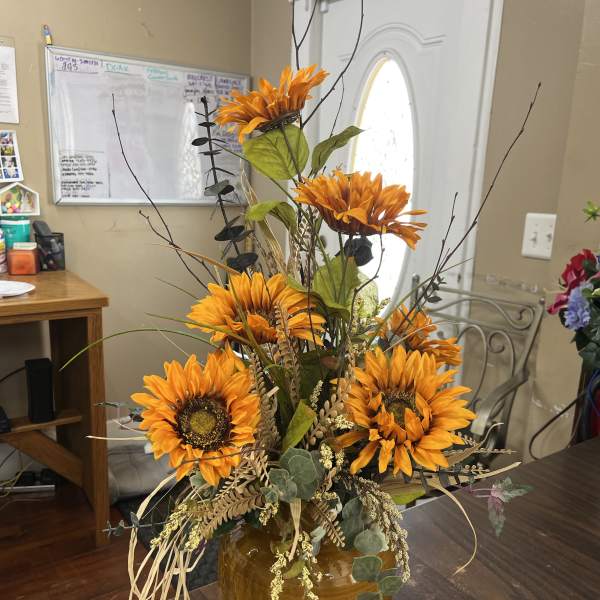 Orange sunflower arrangement in a brown ceramic vase