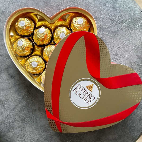 Heart-shaped box of gold-wrapped chocolates with a red ribbon