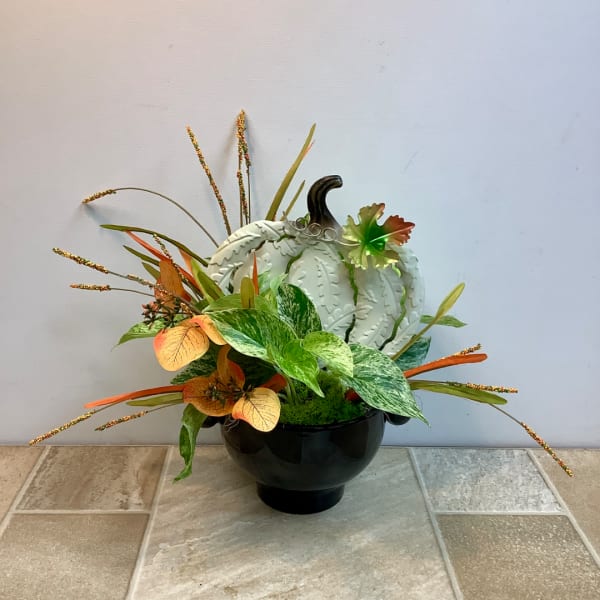 Decorative pumpkin arrangement in a black bowl with autumn leaves