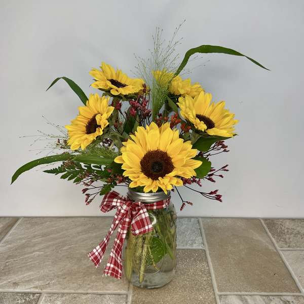 Sunflower arrangement in a mason jar with a red plaid ribbon