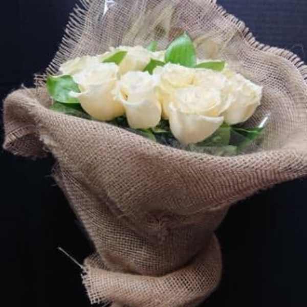 Bouquet of white roses wrapped in burlap