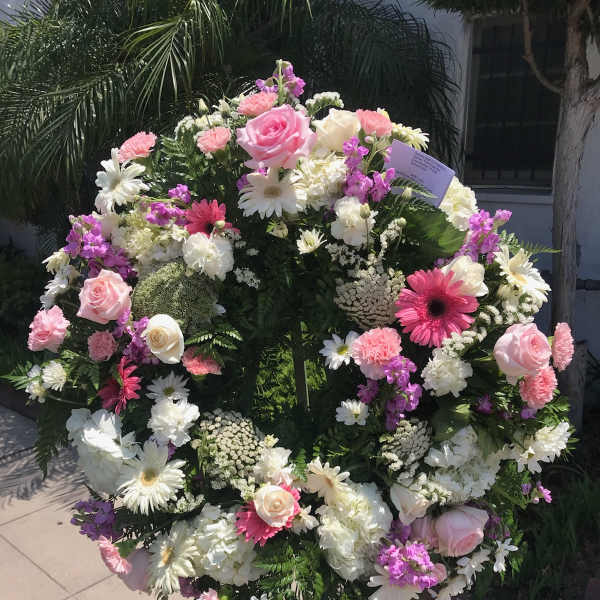 Large standing floral wreath with pink, white, and purple blooms