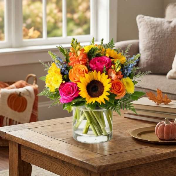 Bright mixed bouquet in a clear glass vase with sunflowers and roses