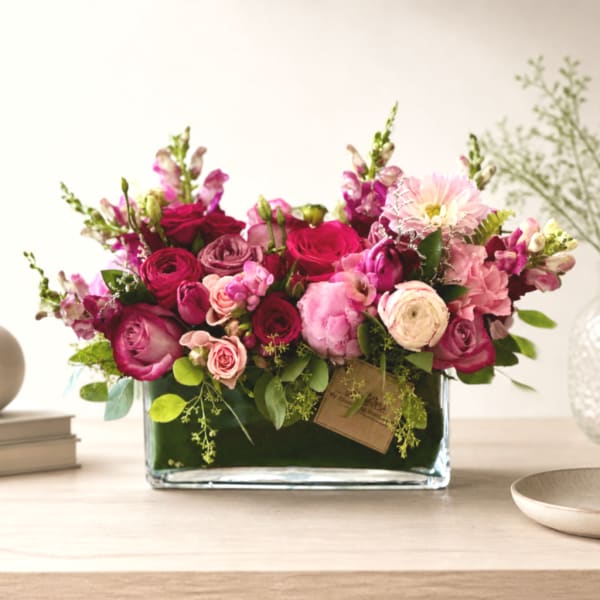 Pink and magenta flower arrangement in a rectangular glass vase