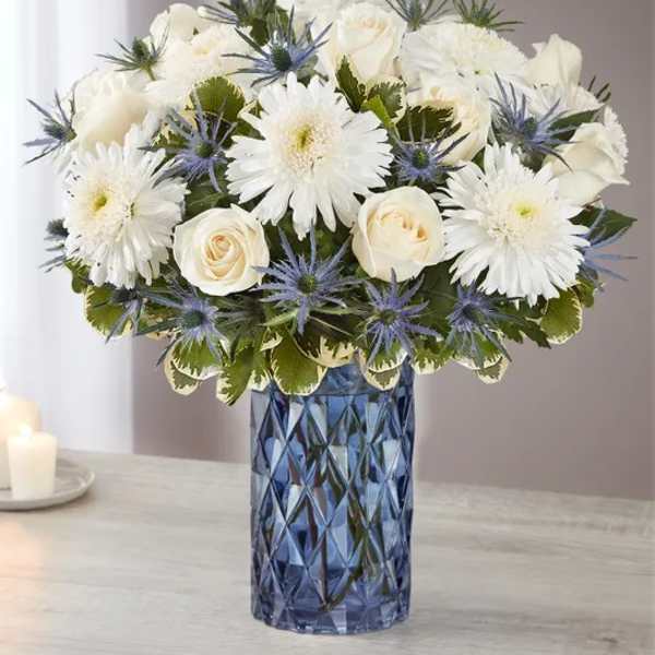 White roses and daisies in a blue glass vase