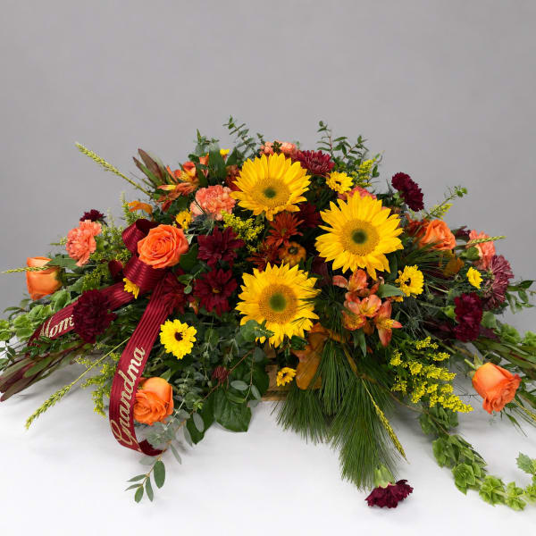 Large floral spray with sunflowers, orange roses, and burgundy blooms