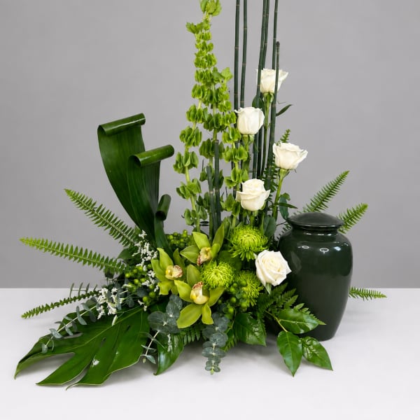 Green floral arrangement with white roses in a dark vase