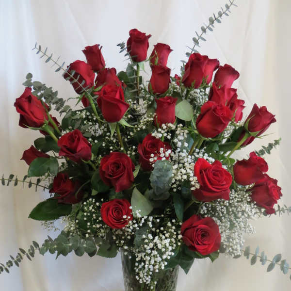 Red roses arranged in a clear glass vase with baby's breath