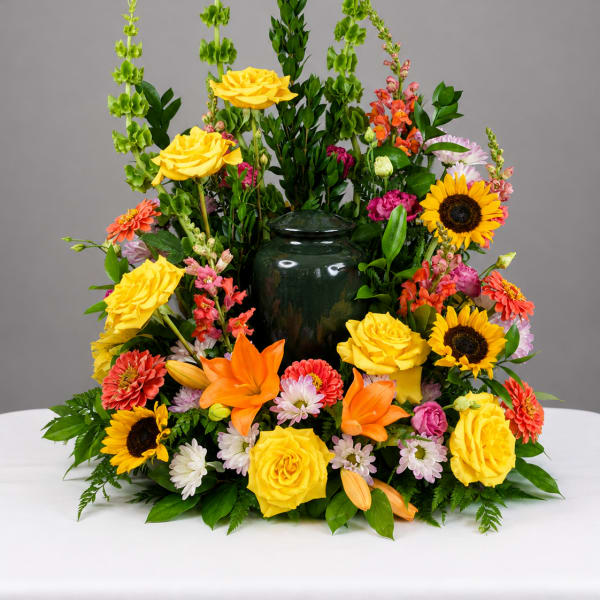 Colorful floral arrangement with yellow roses, sunflowers, and orange lilies in a dark vase
